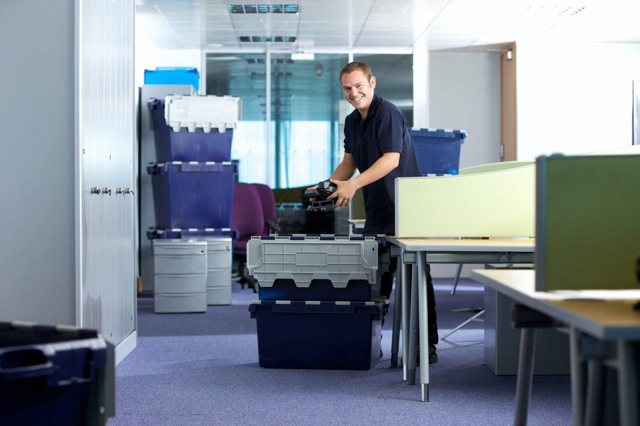 A professional removal man loading delivery crates into a moving truck, showcasing the positive and professional approach of BRG Office Movers. This image highlights their expertise in commercial moving, office relocation services, and efficient business relocation solutions nationwide, ensuring a smooth and stress-free move for clients